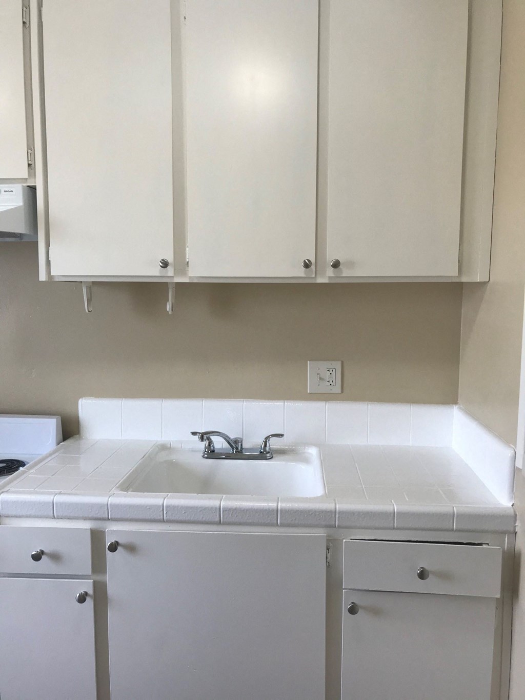 an empty kitchen with white cabinets and a sink