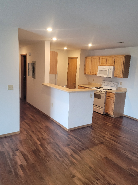 an empty kitchen with wooden floors and a white counter top