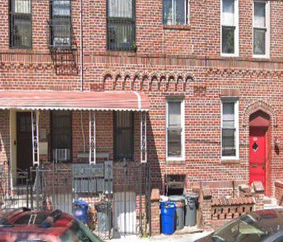 A red brick building with a red door and a red car parked in front.