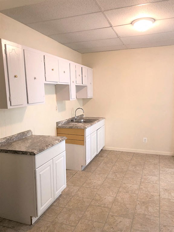 an empty kitchen with white cabinets and a sink