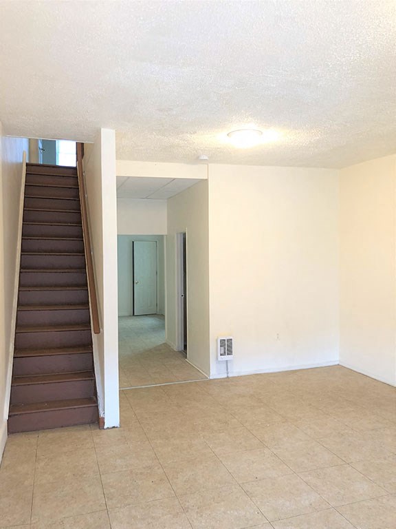 an empty living room with a staircase and a white wall