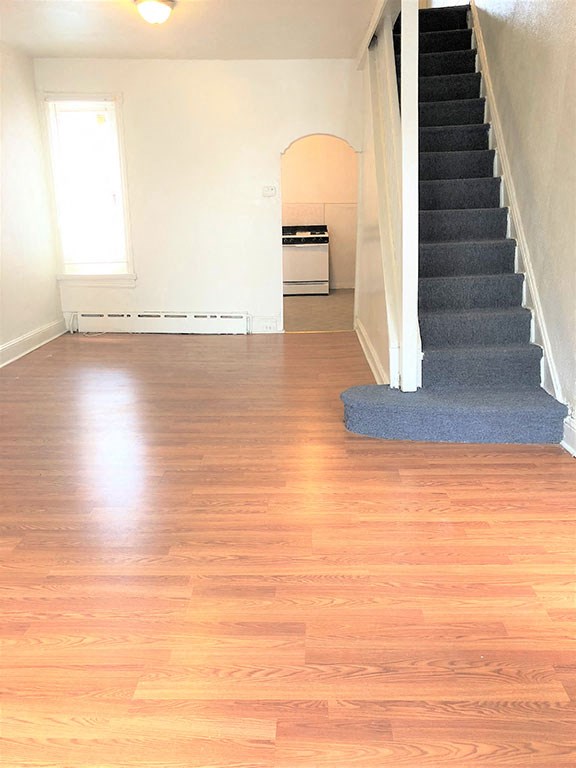 a living room with a staircase and a hard wood floor