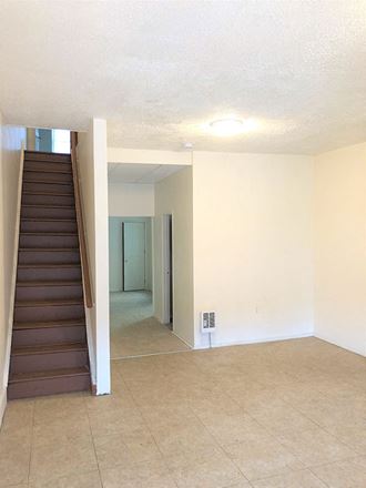 an empty living room with a staircase in a house