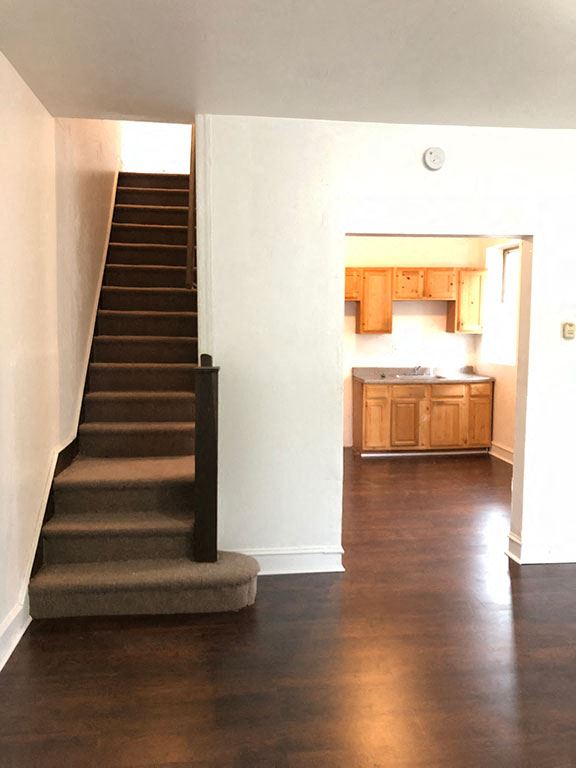 an empty house with stairs and a kitchen in it