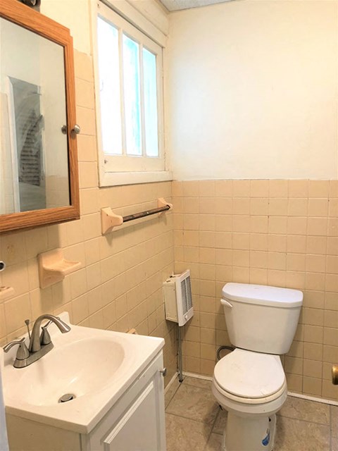 A white toilet in a bathroom with a sink and mirror.