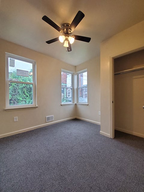 A room with a ceiling fan and carpeted floor.