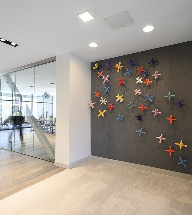 a wall of colorful crosses is in the lobby of an office building