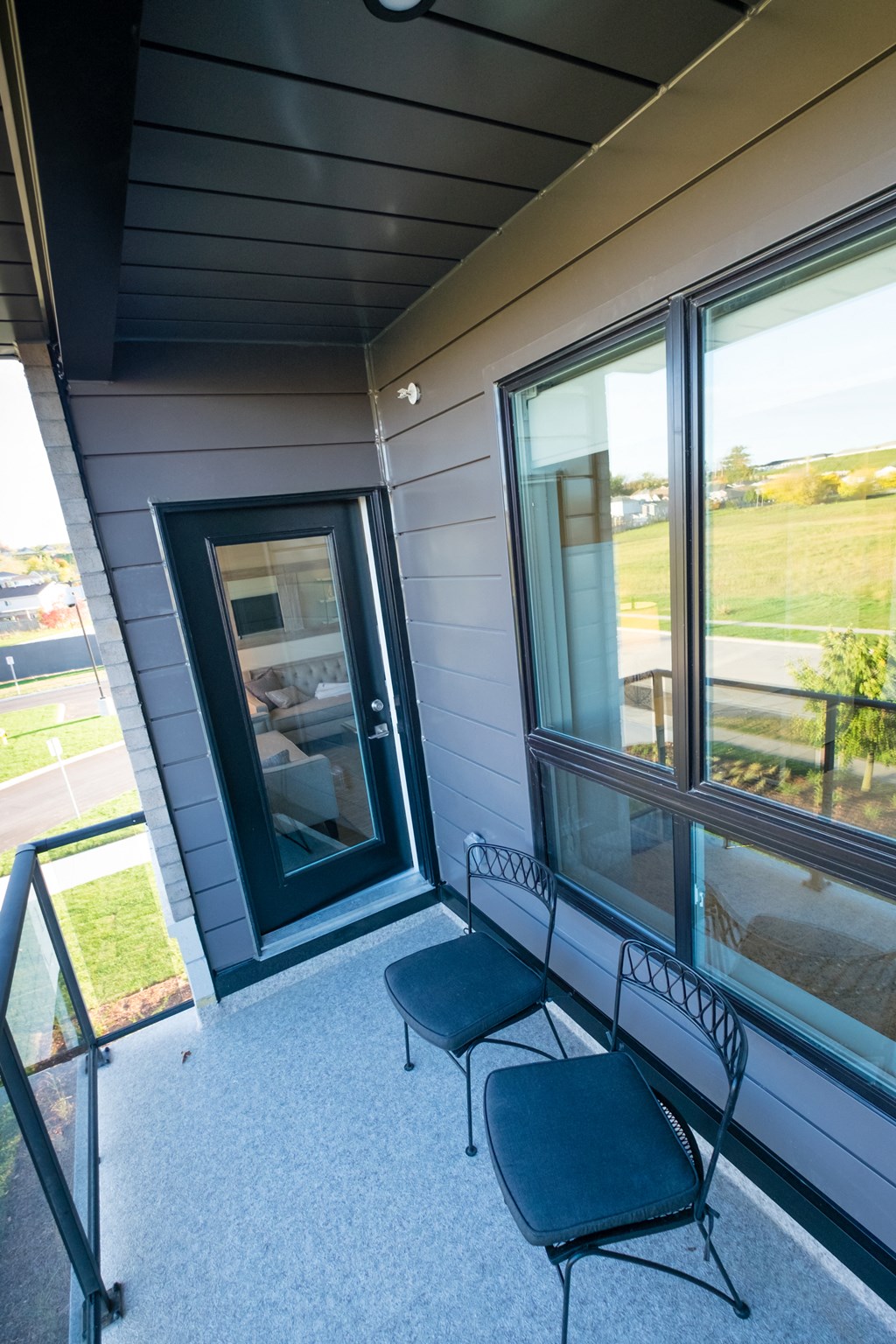 front porch of a house with two chairs and large windows