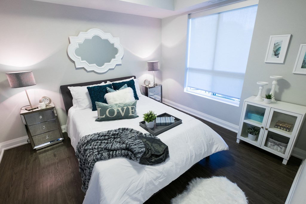 a bedroom with white bedding and pillows and a window