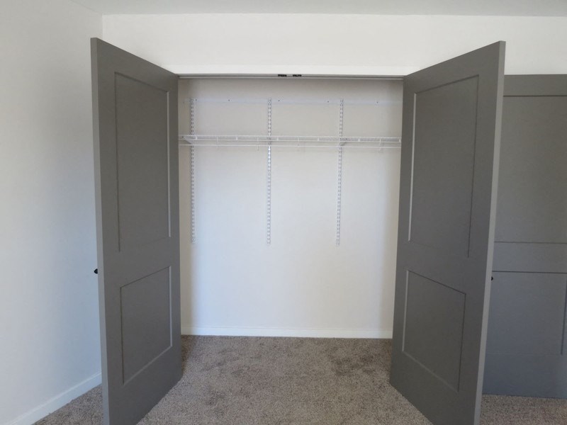 an empty closet with two doors and a white wall