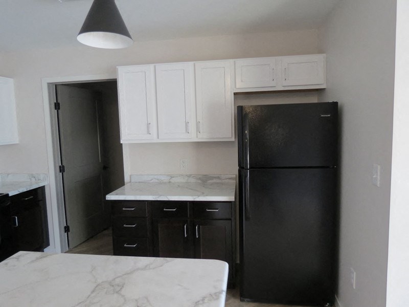 a kitchen with white cabinets and a black refrigerator