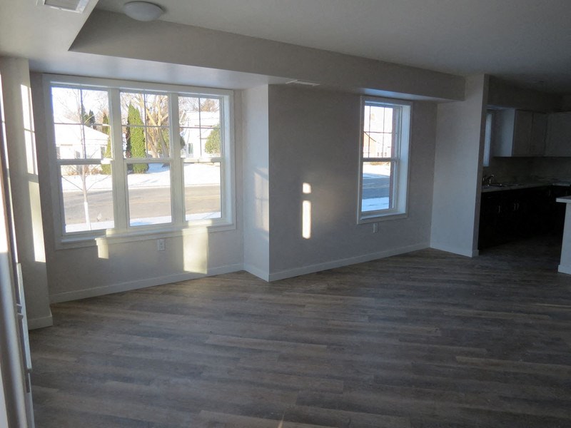 an empty living room with a wooden floor and large windows