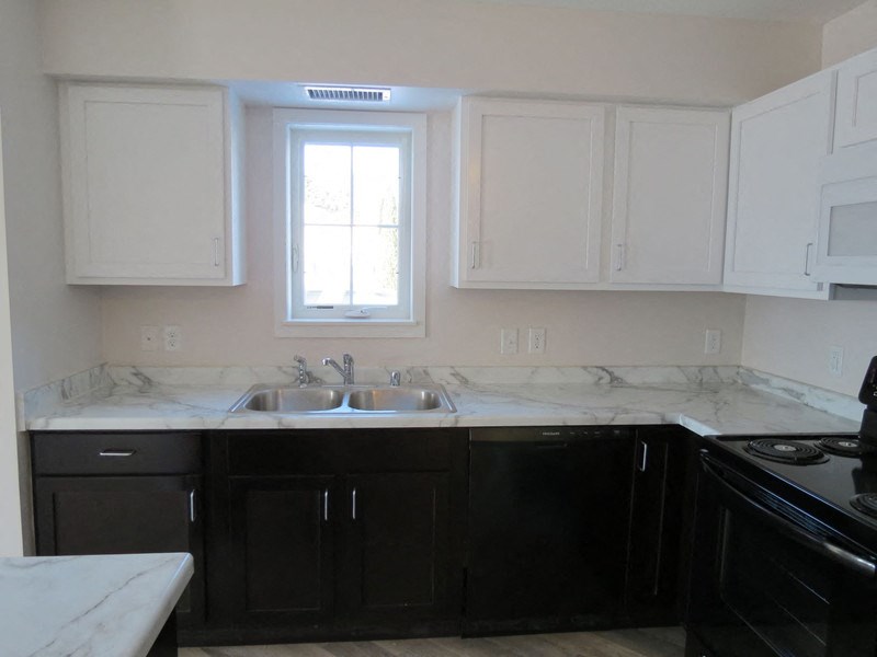 a kitchen with white marble counter tops and black appliances