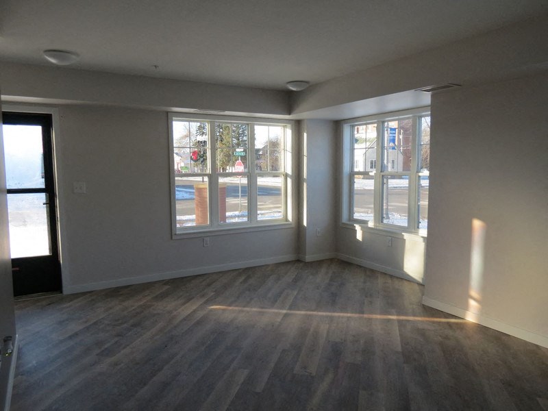an empty living room with wood floors and large windows
