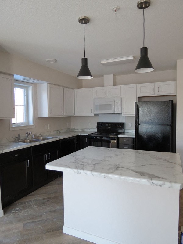 a white kitchen with black appliances and white counter tops