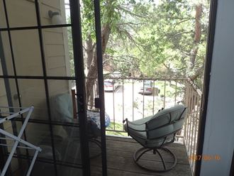 a balcony with a rocking chair and a tree
