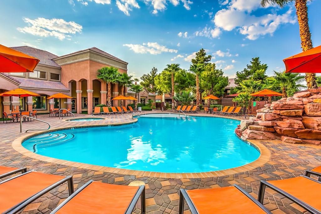 a swimming pool at a resort with chairs and umbrellas