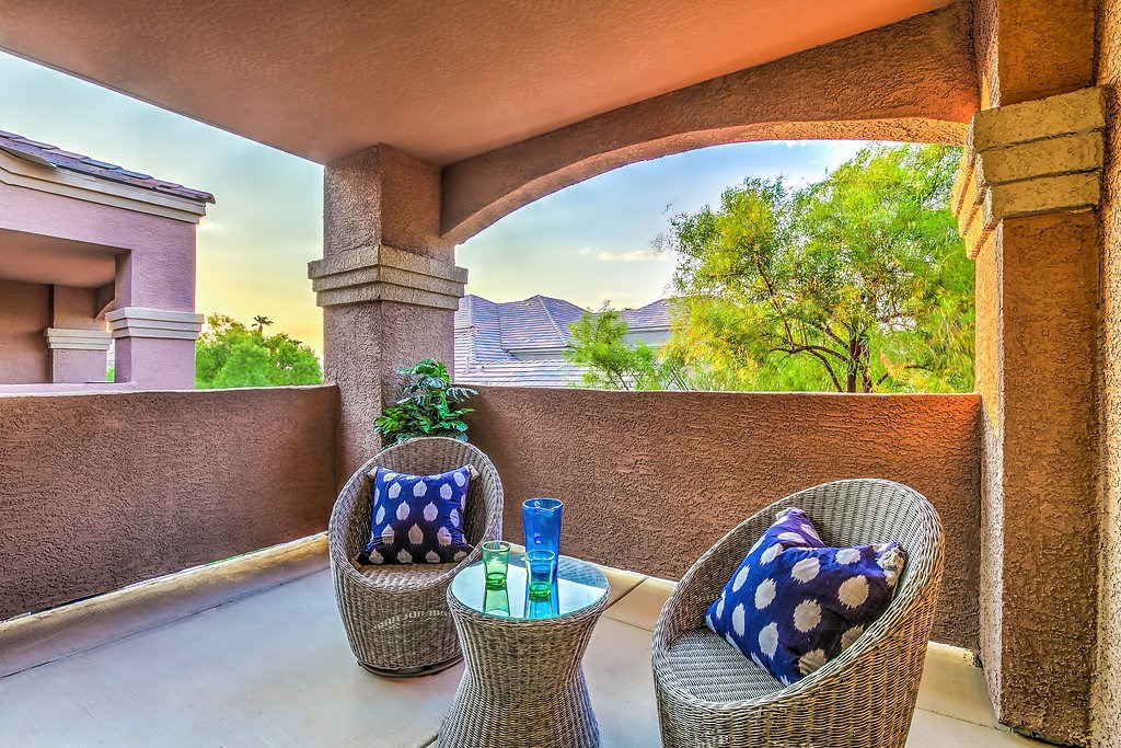 a patio with wicker chairs and a table on a balcony