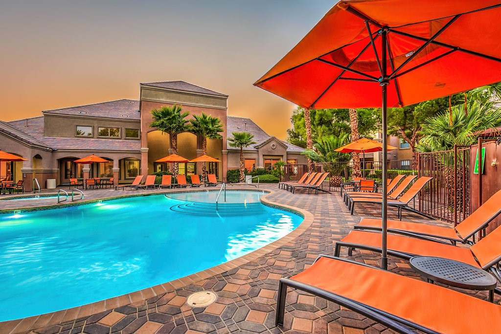 a swimming pool at a resort with chairs and umbrellas