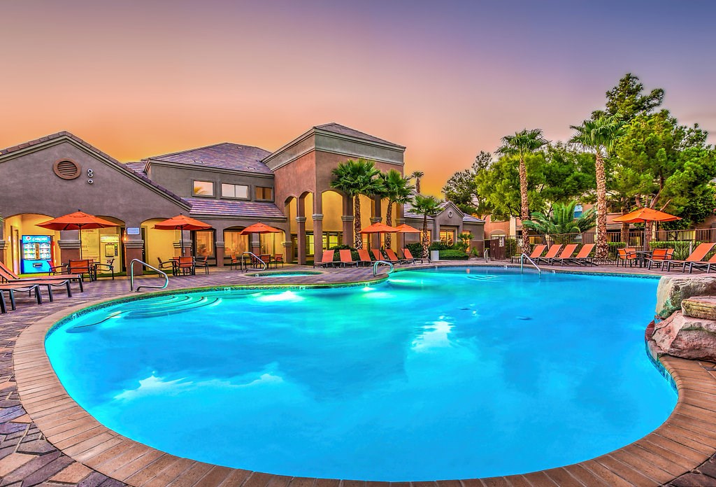 a large swimming pool with a house in the background