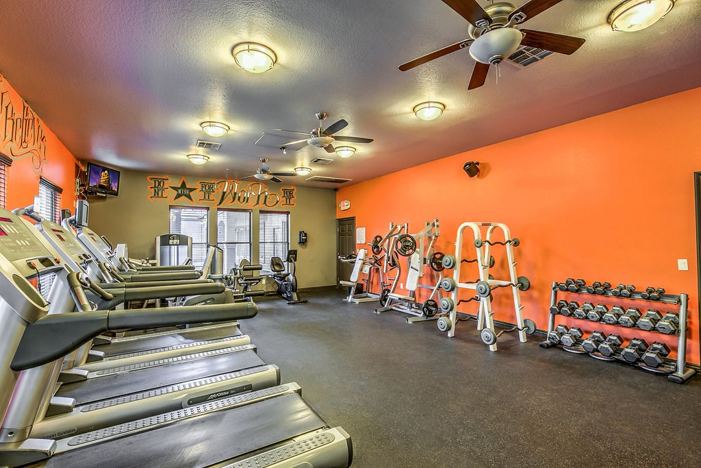 a gym with cardio equipment and a ceiling fan