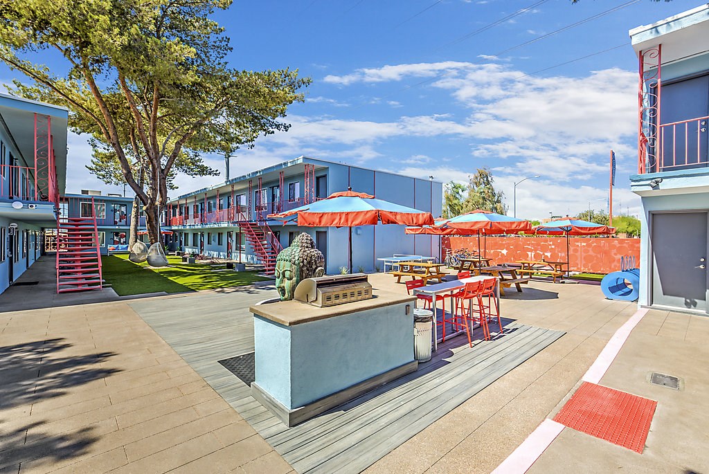 a patio area with umbrellas and tables and a grill