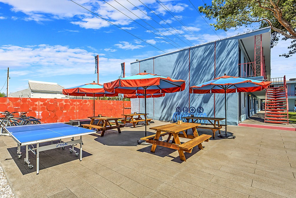 a patio with tables and umbrellas and a ping pong table