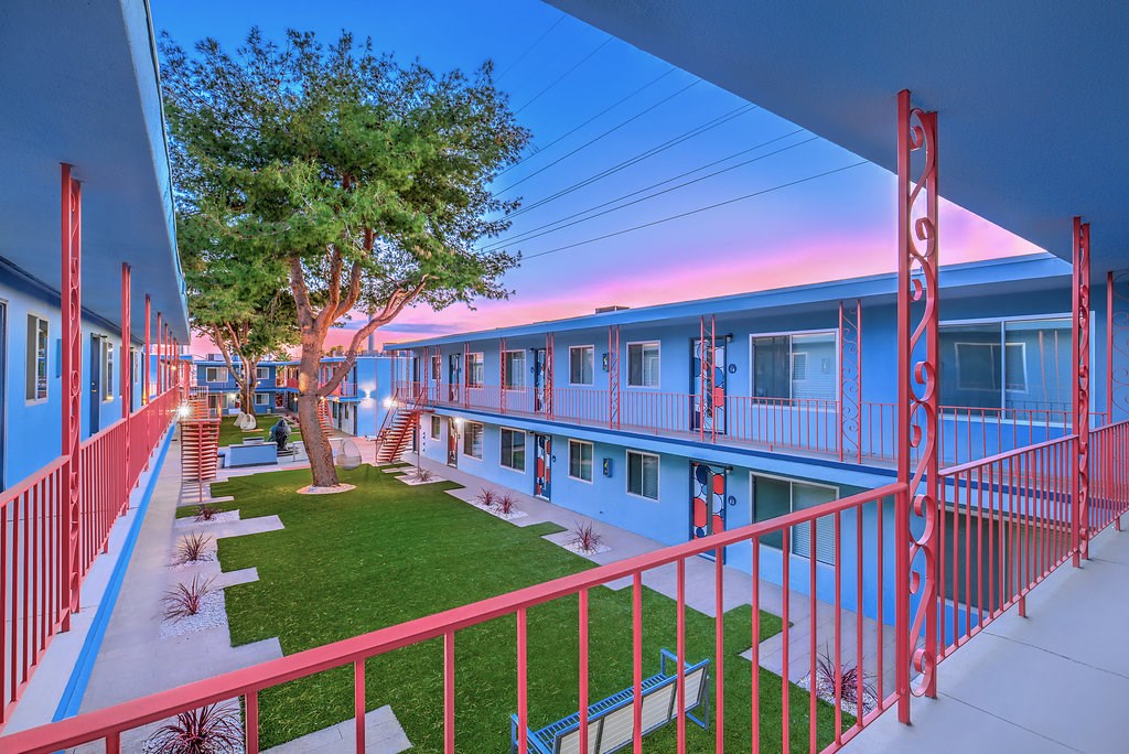 the courtyard of a building with red railing and a tree in front of it
