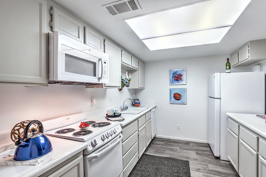 a kitchen with white cabinets and appliances and a white refrigerator