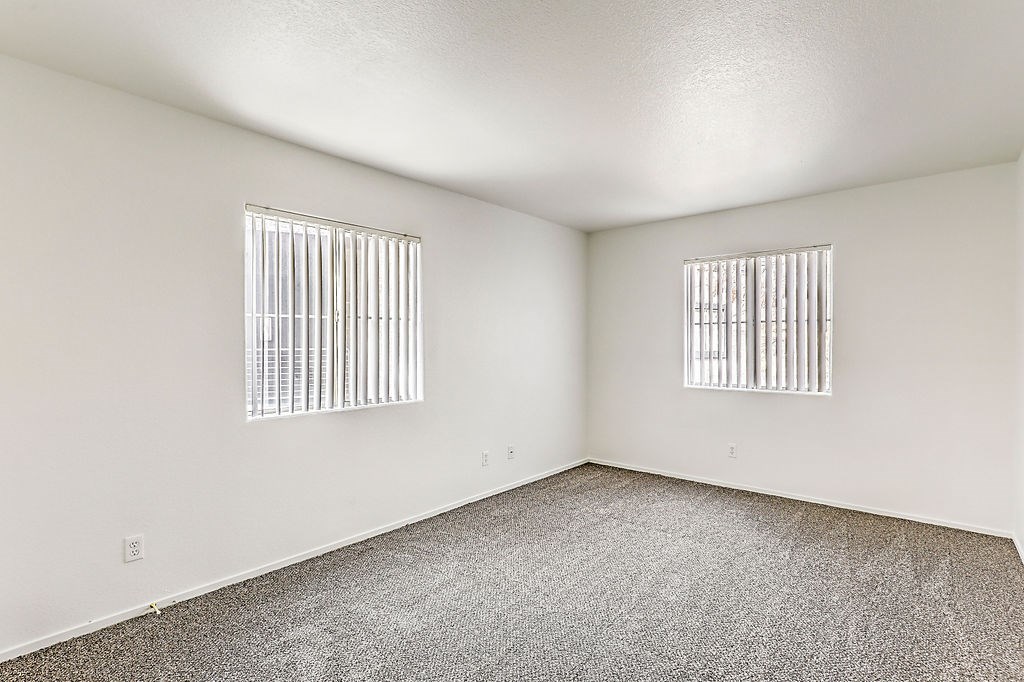 an empty room with two windows and a carpeted floor