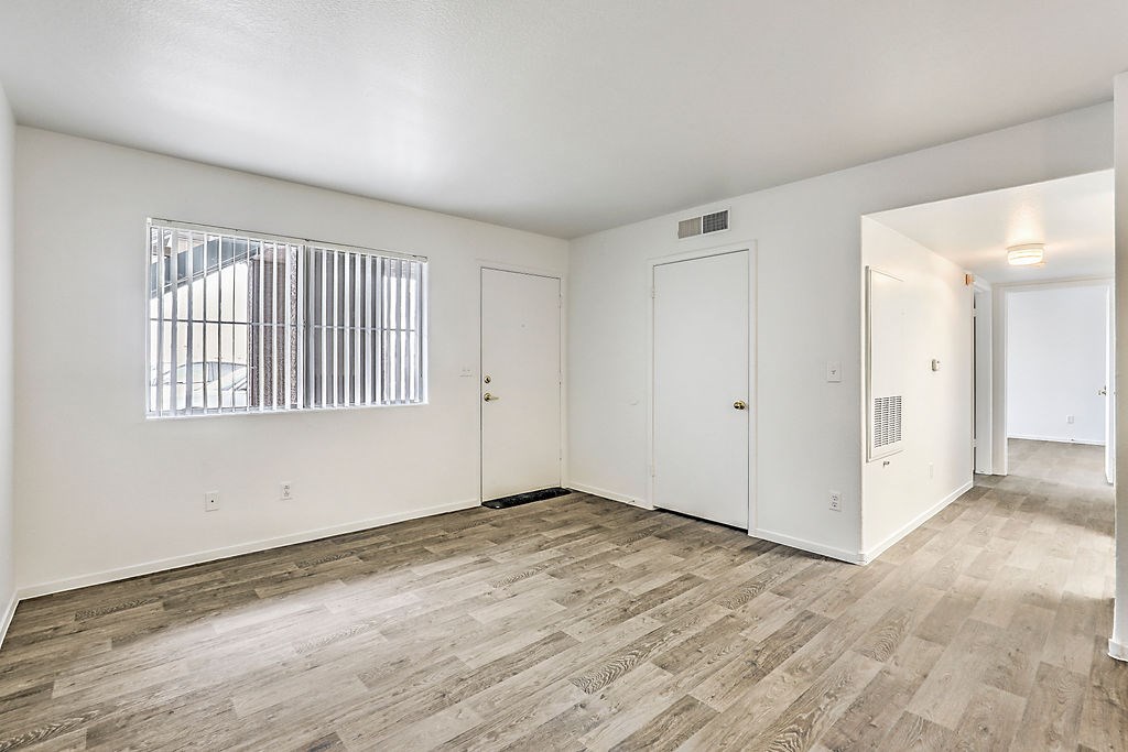 an empty living room with white walls and wood flooring