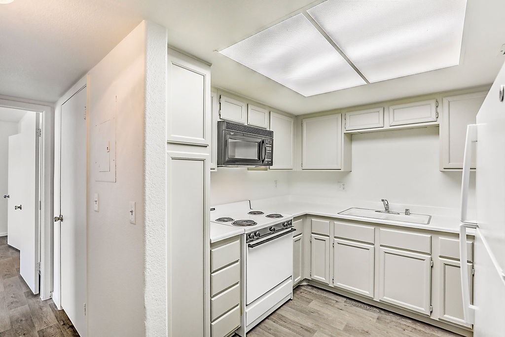 an empty kitchen with white cabinets and white appliances