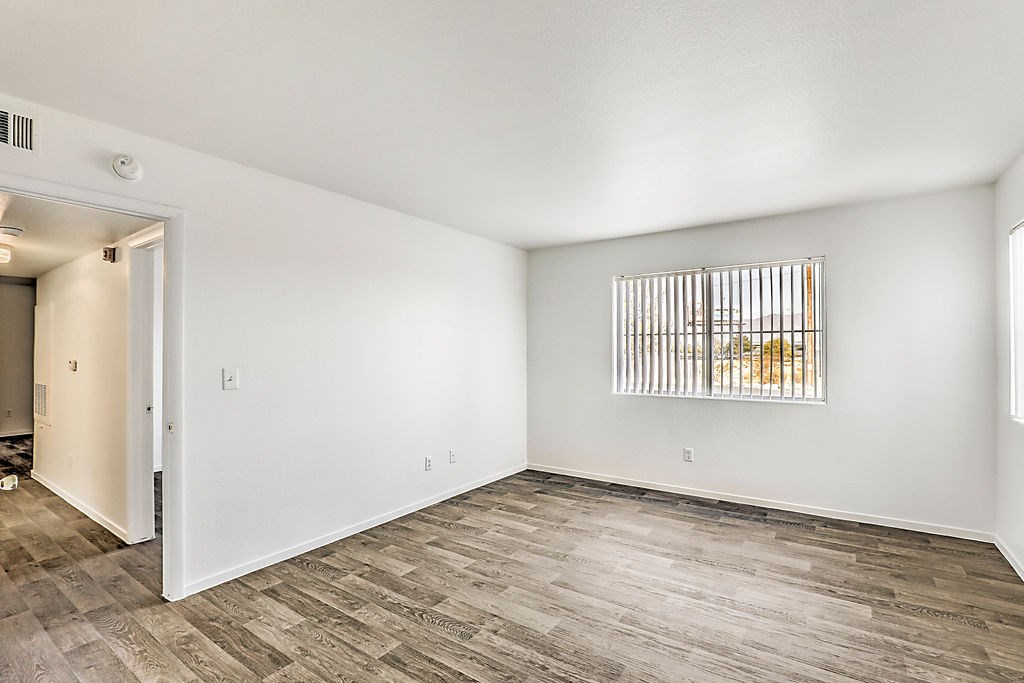 an empty living room with wood flooring and a window