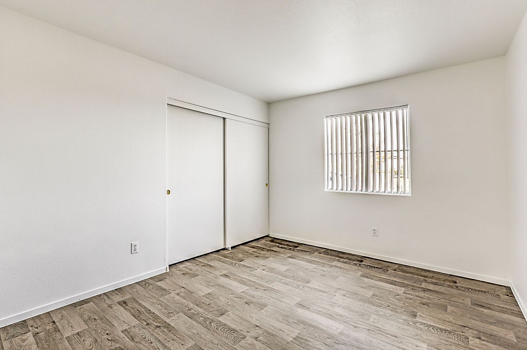 an empty bedroom with wood flooring and a window