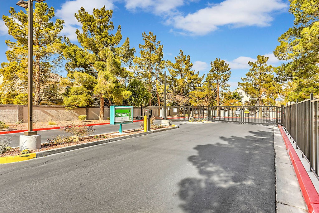 the entrance to a parking lot with trees and a fence