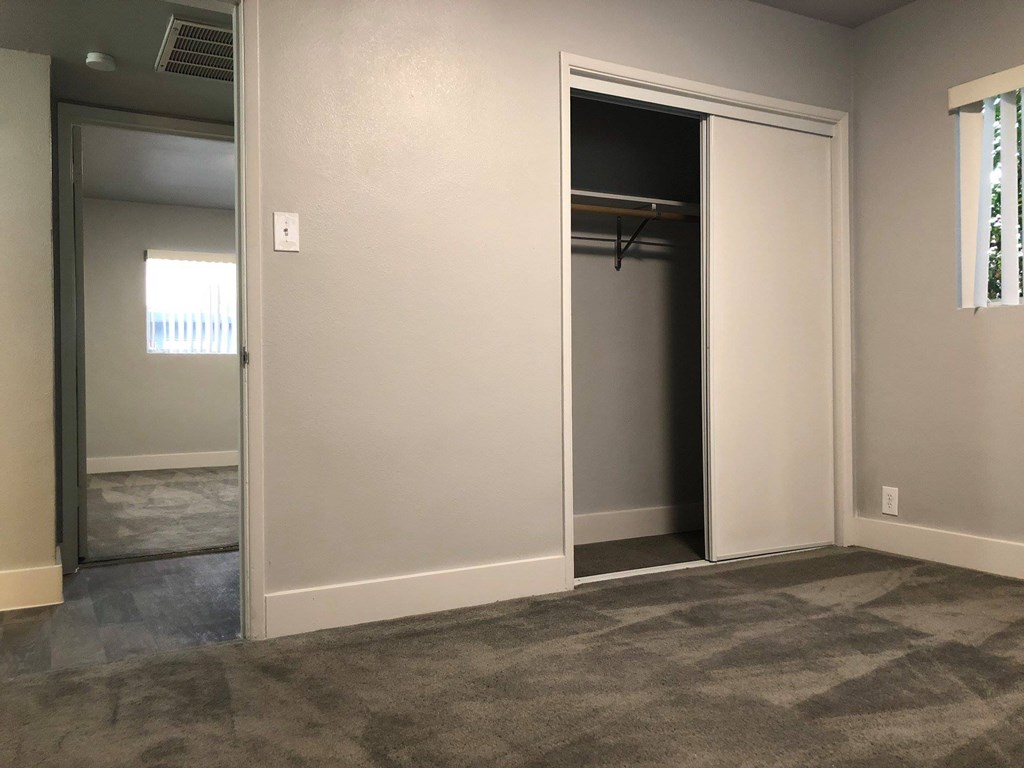 an empty room with a closet and a door to a hallway