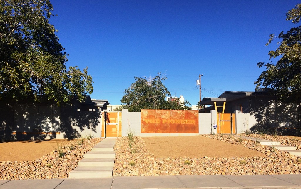 the front yard of a house with a orange fence and a gate