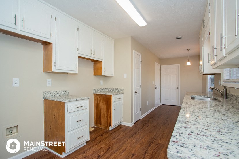 a kitchen with white cabinets and counter tops and a wood floor