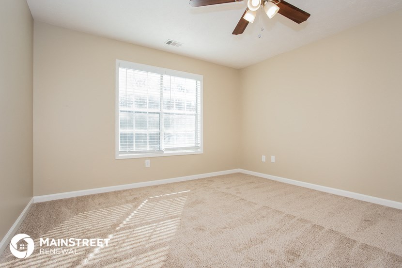 the spacious living room with carpeting and a ceiling fan