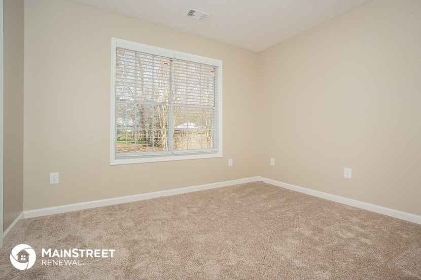 the upstairs bedroom has a large window and carpeted flooring