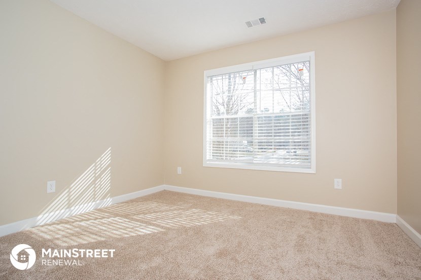 a bedroom with a large window and a carpeted floor