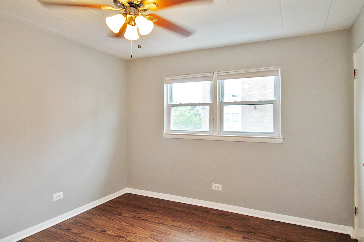 an empty room with a ceiling fan and a window