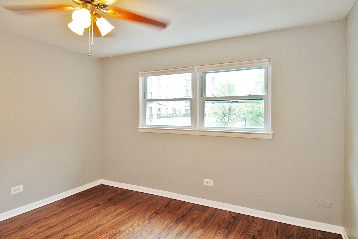 an empty room with a window and a ceiling fan