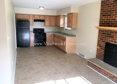 A kitchen with a black refrigerator and wooden cabinets.