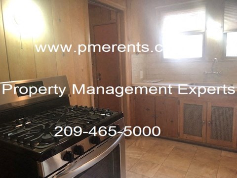 A kitchen with a stove and a website address for property management experts.