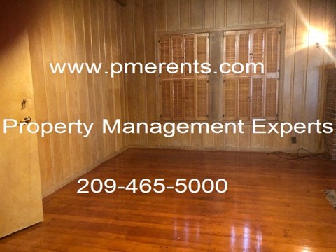 A room with wooden floors and walls, with a light source coming from the top right corner.