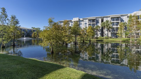 a building overlooking a pond with trees and a fountain