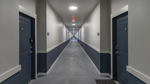 a hallway with blue doors and white walls and a long corridor with a red light