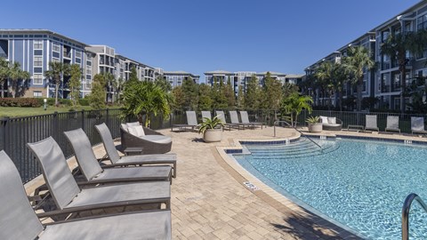 a swimming pool with lounge chairs next to an apartment building