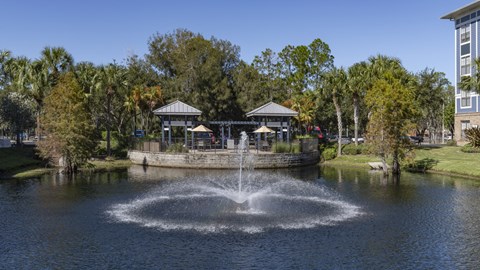 a fountain in the middle of a pond in a park